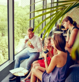 Monkey Bar people drink drinks in seats with cushions and small tables facing large windows