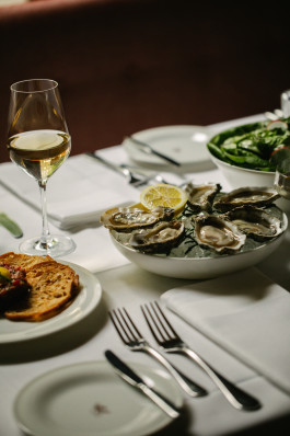 Le Petit Royal table photo, oysters on the main plate, other dishes, cutlery and wine glasses partially visible nearby