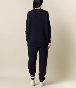 woman posing from behind in black sweatshirt, black sweatpants and white socks