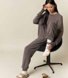 woman posing sitting on chair in grey t-shirt, grey sweatpants and beige sandals